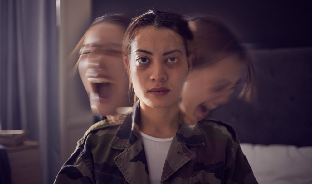 Eine junge Frau blickt ruhig und unbewegt nach vorn, während links und rechts von ihr verschwommene, schreiende Versionen ihres Gesichts auftauchen. Das Bild vermittelt einen starken Kontrast zwischen äußerer Kontrolle und innerem Chaos.
